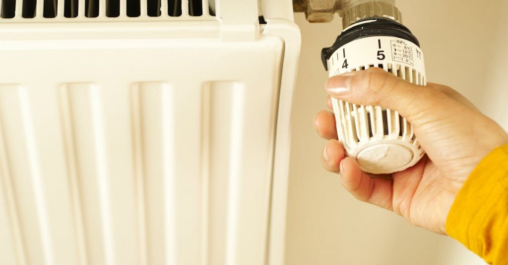 Close-up of hand adjusting radiator thermostat to control home heating temperature.