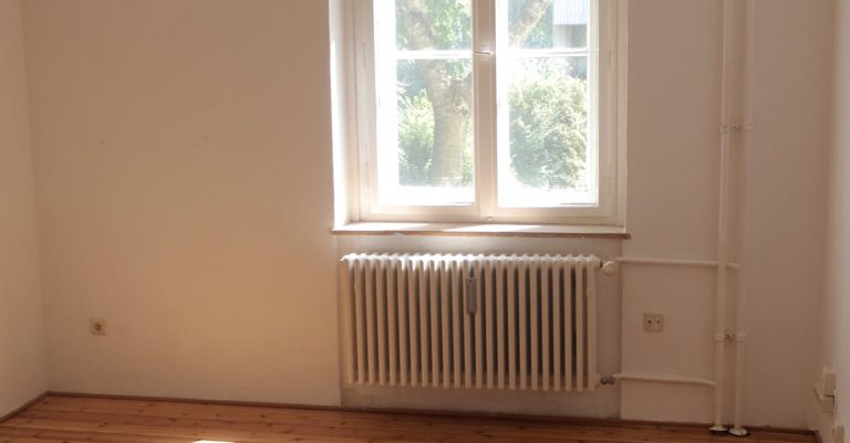 Spacious empty room with wooden floor and large window in Berlin, ideal for interior planning.